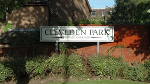 Un panneau indiquant « Clevden Park – propriété privée », avec un mur de briques et de la verdure en arrière-plan.