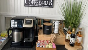 Disposición de una barra de café con una máquina de café, recipientes de azúcar y tazas.