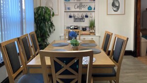 Un comedor con mesa y sillas de madera, una araña y decoración temática de café en la pared.