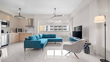 A modern living room with a sectional sofa, a dining area, and a kitchen.