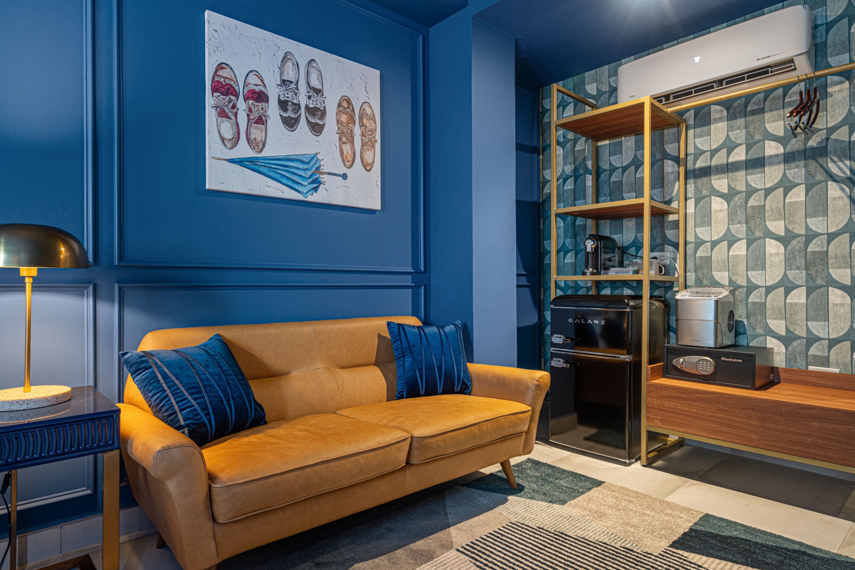 Un salon moderne avec un mur bleu, un canapé marron, une machine à café et une bibliothèque.