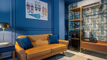 Un salon moderne avec un mur bleu, un canapé marron, une machine à café et une bibliothèque.