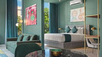 Un dormitorio moderno con una cama grande, un sofá, una mesa de comedor y obras de arte en las paredes.