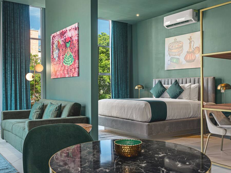 Un dormitorio moderno con una cama grande, un sofá, una mesa de comedor y obras de arte en las paredes.