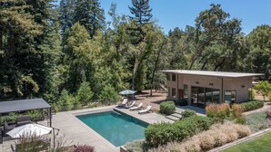 Una casa moderna con piscina, rodeada de un bosque denso.