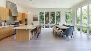 Una cocina moderna con una isla grande, armarios de madera y un comedor con una mesa larga y sillas.