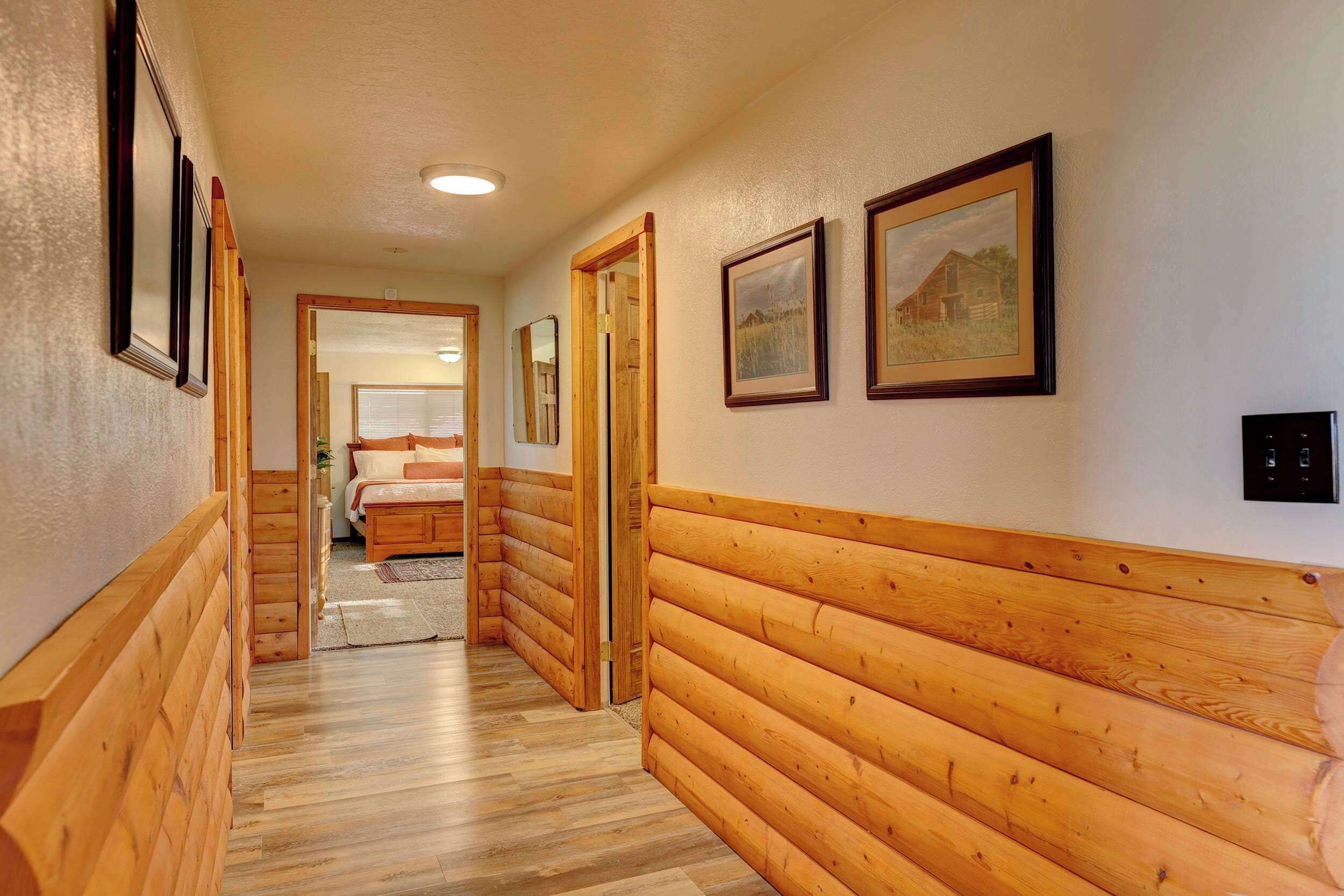 A hallway with wooden paneling and framed pictures on the walls.