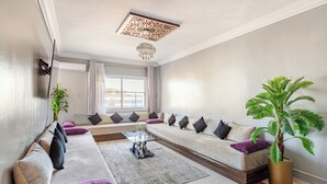 Una sala de estar moderna con un conjunto de sofás, una mesita de centro y una planta grande en maceta.