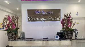 A hotel reception desk with a 'Welcome Cataleya Hotel' sign, two orchid vases, a digital screen, and a 'direct' sign on the wall. - Hotel Cataleya BV (Almere)