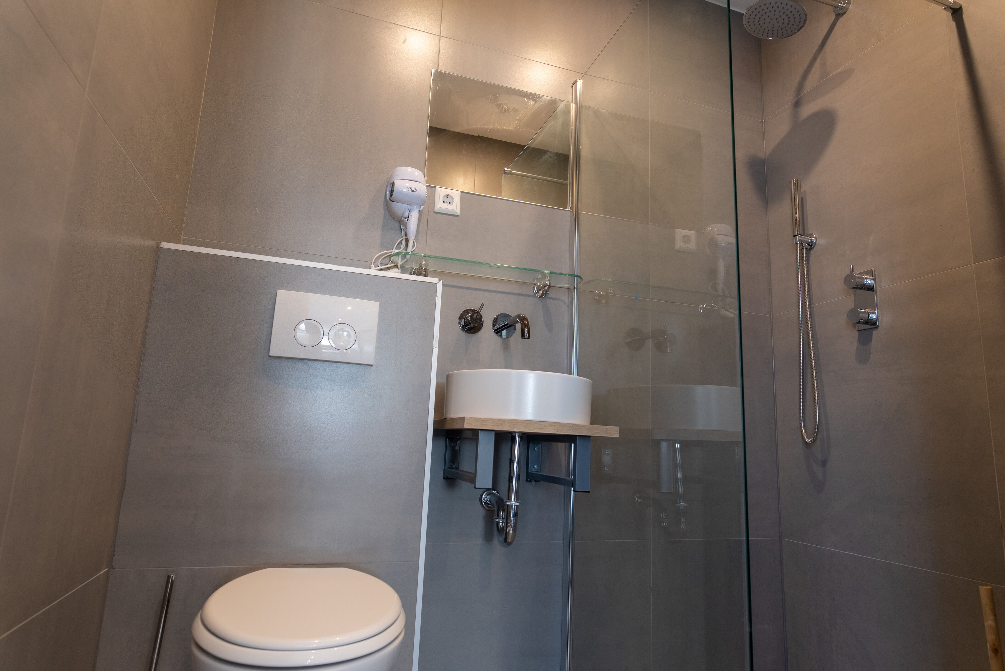 A modern bathroom with a glass shower enclosure, a white toilet, and a sink with a mirror above it.