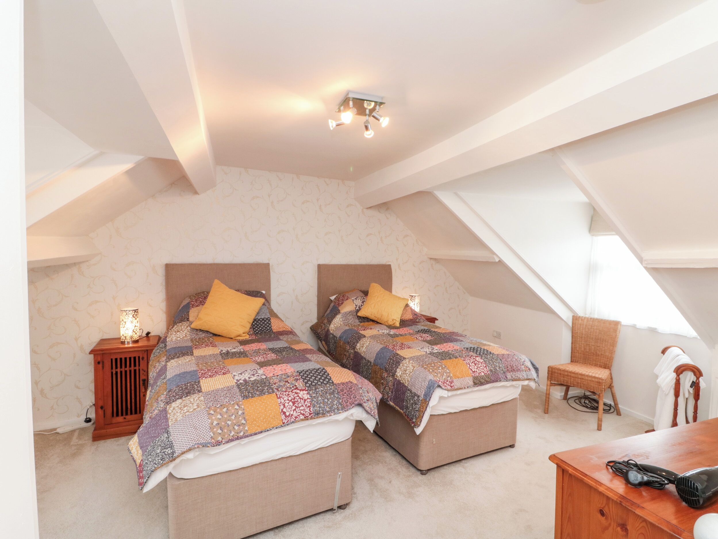 A bedroom with two beds, a nightstand, a chair, and a dresser.