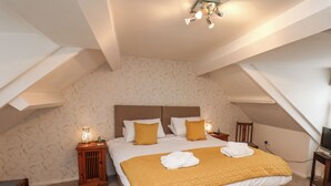 A bedroom with a large bed, two nightstands, a wooden chair, and a television on a stand. - Bluebell Cottage (Bridlington)