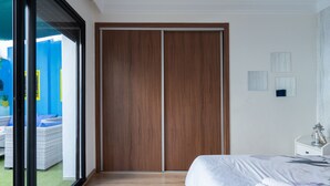A modern bedroom with a large sliding door, a bed with white bedding, and a view of an outdoor area with wicker furniture. - Majorelle - Daily rental Casablanca (Casablanca)