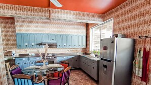 Een keuken met blauwe kastjes, een glazen tafel en een roestvrijstalen koelkast.