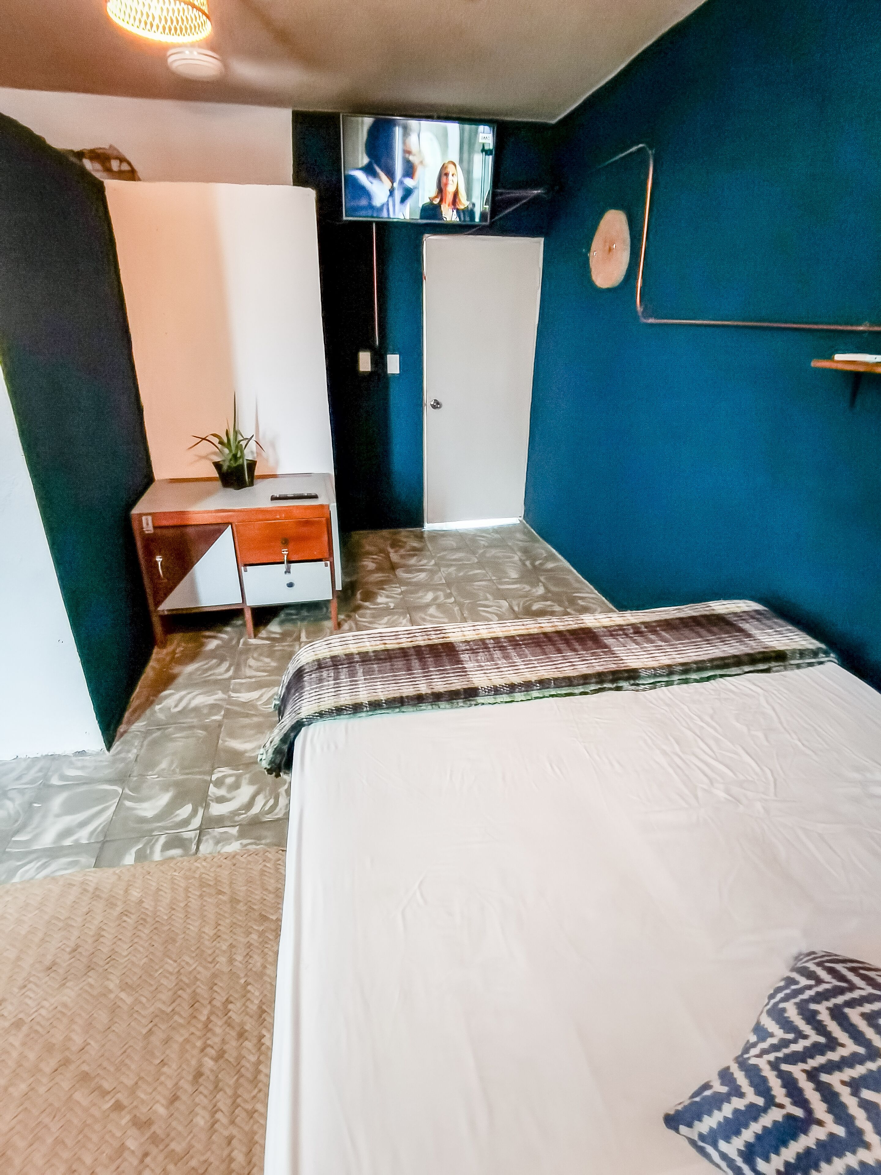 Un dormitorio con cama, escritorio, televisor y puerta.