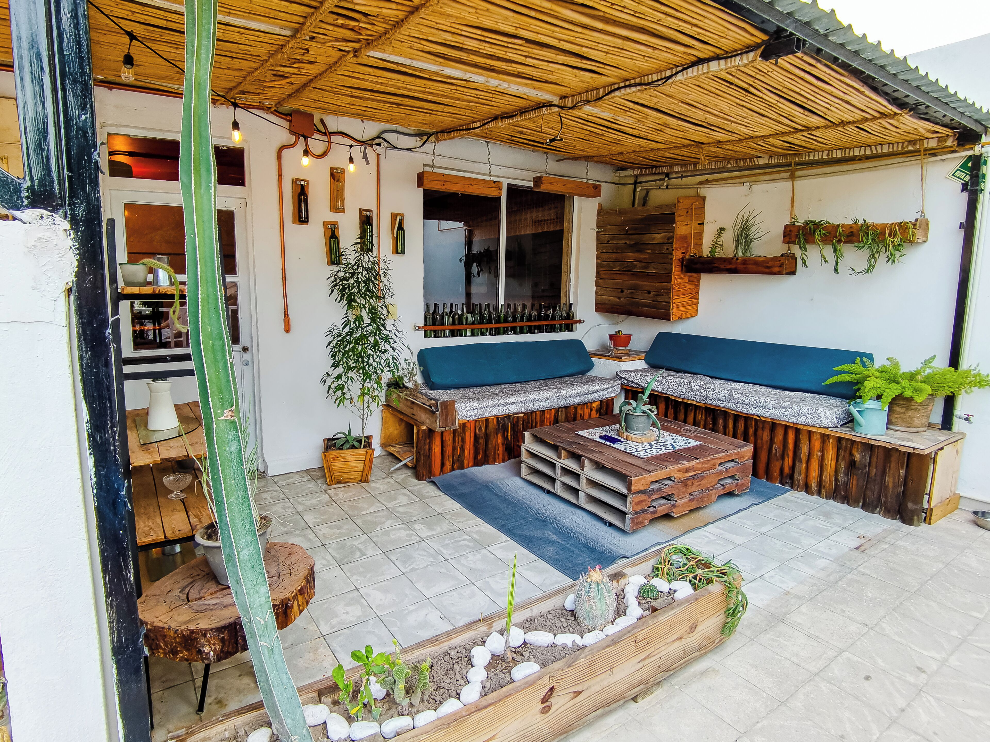 A cozy outdoor seating area with wooden furniture, a thatched roof, and potted plants.