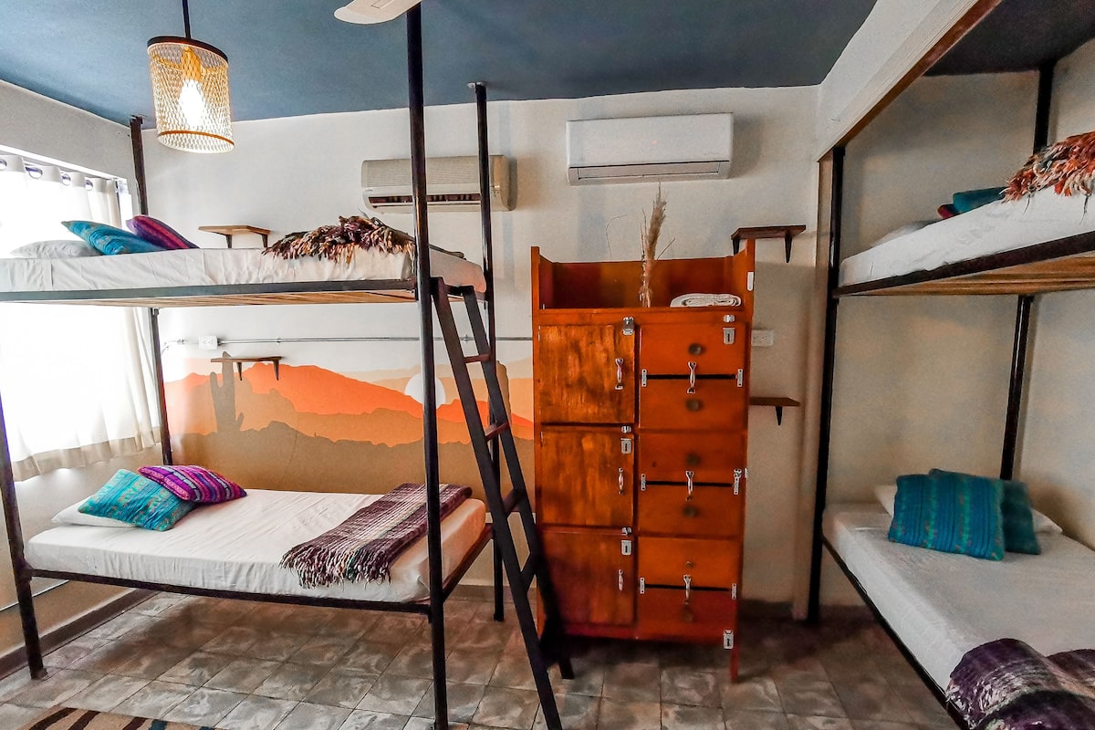 Un dormitorio con literas, un aparador de madera y un mural en la pared.
