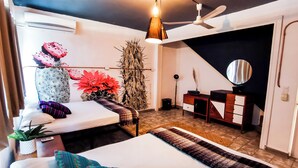 Een moderne slaapkamer met een bed, nachtkastje, dressoir en een plafondventilator.