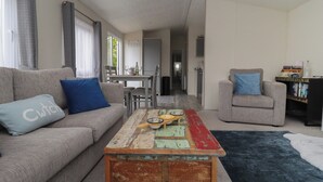 Un salon comprenant un canapé, un fauteuil, une table basse et une bibliothèque.