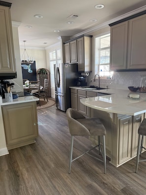 A modern kitchen with a central island, stainless steel appliances, and a dining area with a chandelier. - Private beach, secluded three-bedroom, ocean front escape (Ocean Springs)