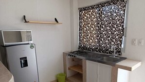 Een kleine keuken met een magnetron, gasfornuis en een klein aanrecht.