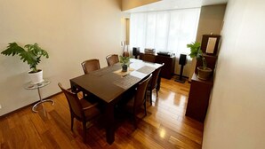 A modern dining area with a wooden table, chairs, and potted plants. - Residenza La Giacca (Tokyo)
