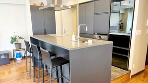 A modern kitchen with a central island, bar stools, and built-in appliances. - Residenza La Giacca (Tokyo)