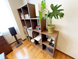 A room with a wooden bookshelf, a potted plant, and a flat-screen TV. - Residenza La Giacca (Tokyo)