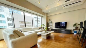 A modern living room with a white sofa, a coffee table, and a TV. - Residenza La Giacca (Tokyo)