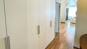 A hallway with a wooden floor leading to a room with a white wardrobe and a door. - Residenza La Giacca (Tokyo)