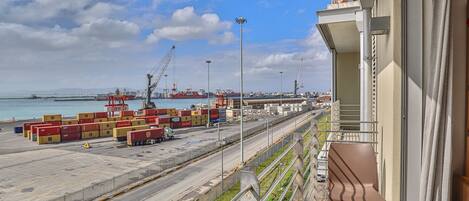 A port with shipping containers, cranes, and a clear sky.