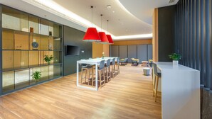 A modern office space with a long white table, red pendant lights, and wooden flooring. - Holiday Inn Express Xinji City Center by IHG (Shijiazhuang)