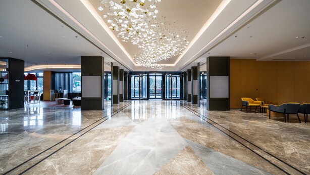 A spacious lobby with a reflective marble floor, modern lighting fixtures, and seating areas. - Holiday Inn Express Xinji City Center by IHG (Shijiazhuang)