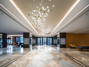 A spacious lobby with a reflective marble floor, modern lighting fixtures, and seating areas. - Holiday Inn Express Xinji City Center by IHG (Shijiazhuang)