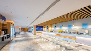A modern hotel lobby with a long reception desk, seating area, and a coffee station. - Holiday Inn Express Xinji City Center by IHG (Shijiazhuang)