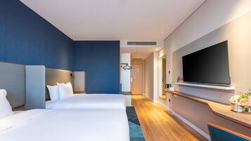 Een moderne hotelkamer met een groot bed, een flatscreen televisie aan de muur en een houten vloer.