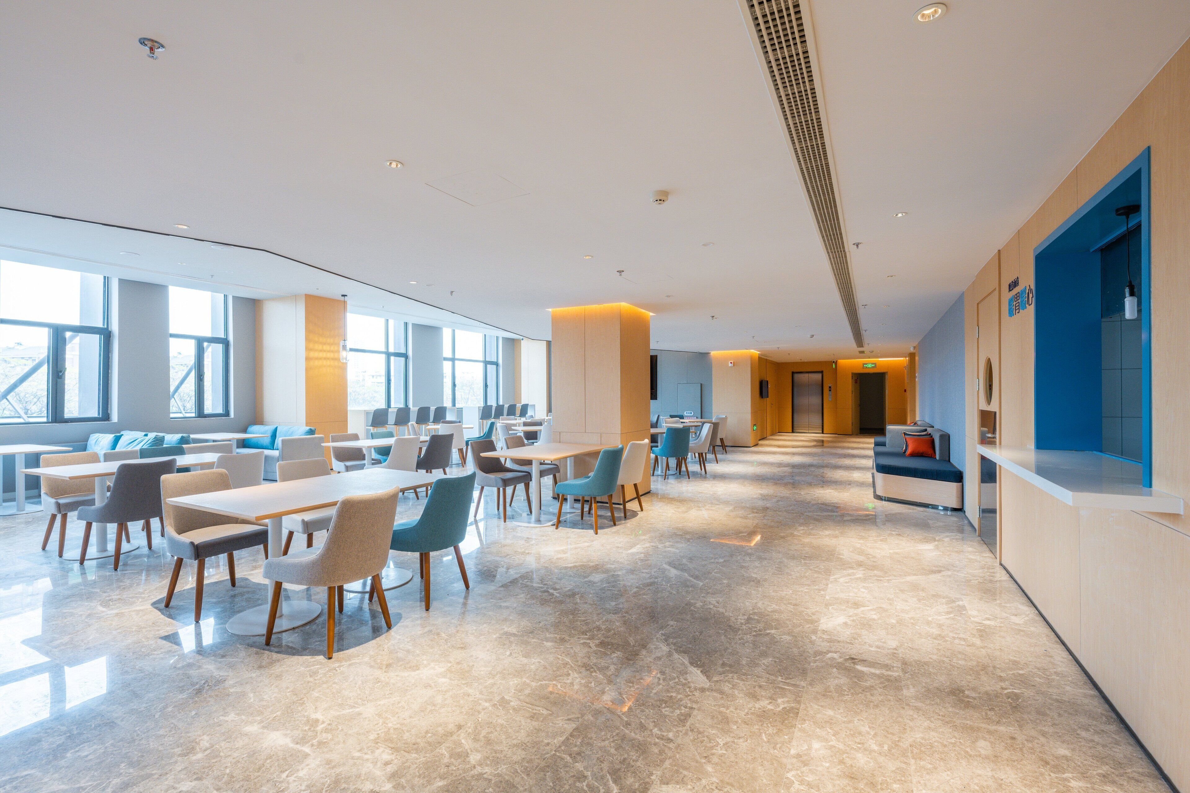A spacious, modern dining area with high ceilings, large windows, and a clean, polished floor.