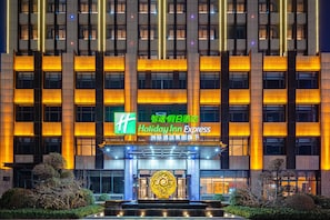 A multi-story hotel with a prominent entrance, illuminated signage, and a decorative sphere at the center.