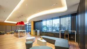 A modern lounge area with seating, a dining area, and large windows offering a city view. - Holiday Inn Express Xinji City Center by IHG (Shijiazhuang)