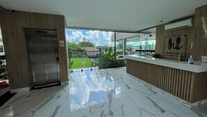 Een moderne hotel lobby met een marmeren vloer, een receptiebalie en een lift.