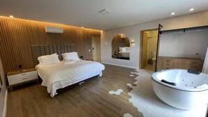 Een moderne hotelkamer met een groot bed, een inloopkast en een aparte badkamer met jacuzzi.