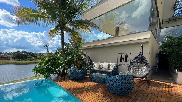 Een modern zwembadgedeelte met een houten terras, blauwe buitenmeubels en een bord met de tekst 'Hotel do Lago'.