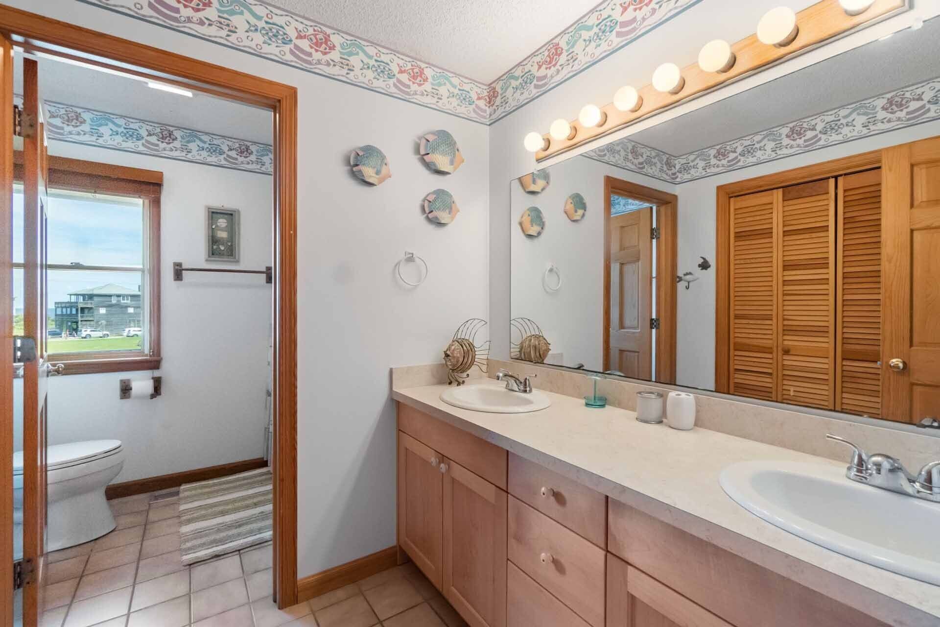 A bathroom with a large mirror, wooden cabinets, a sink, and a toilet.