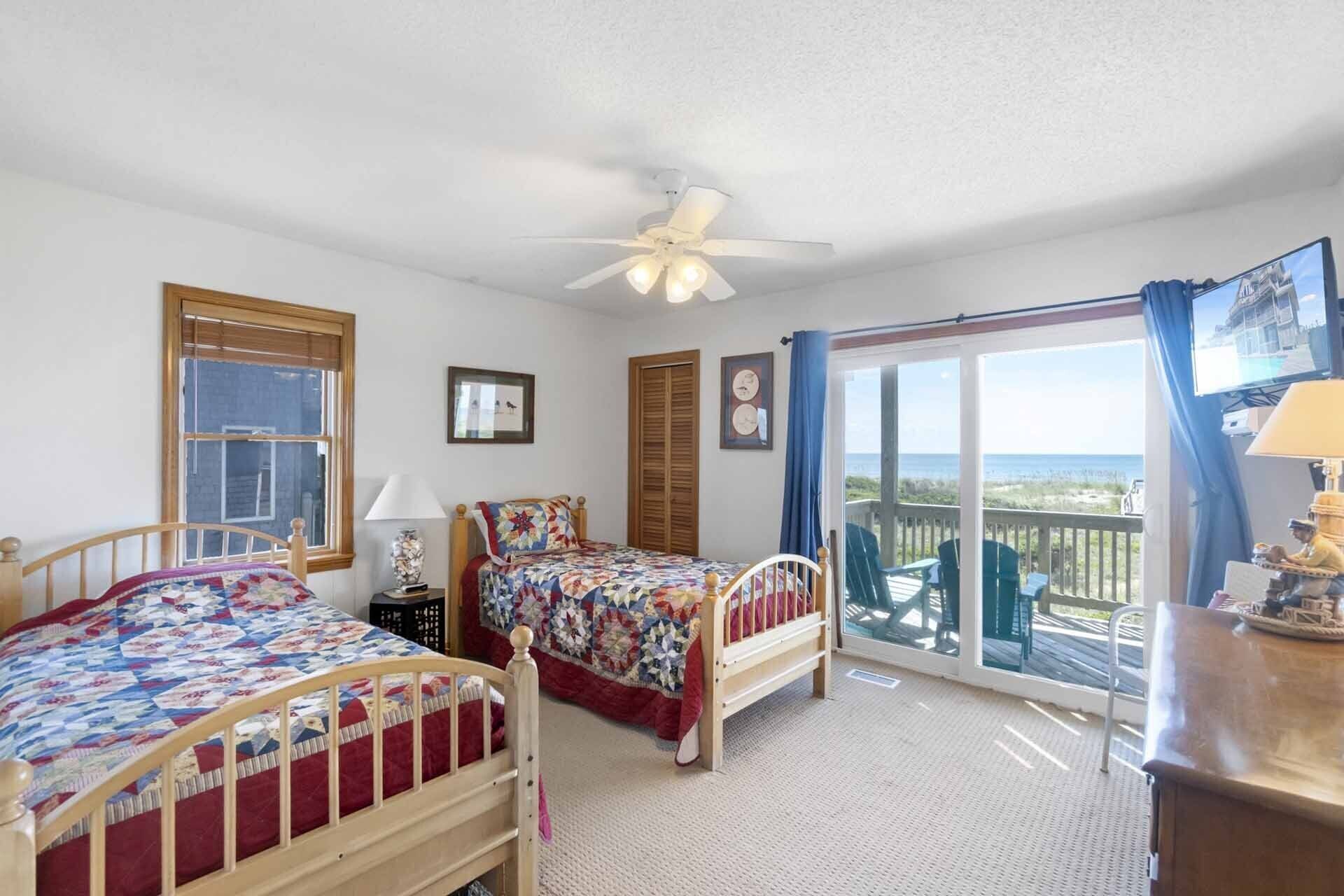 A bedroom with two beds, a ceiling fan, a window, and a balcony with a view.