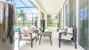 A covered patio area with wicker furniture and a view of a swimming pool. - Relax in Style: Elegant Vacation Home in Orlando (Kissimmee)