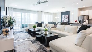 A modern living room with a sofa, coffee table, and a dining area. - Relax in Style: Elegant Vacation Home in Orlando (Kissimmee)
