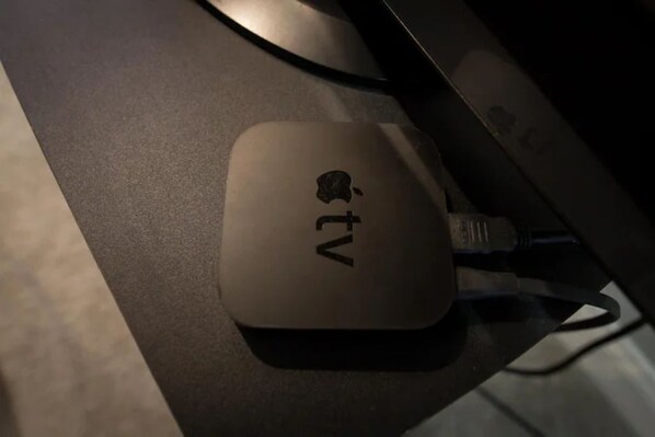 A small, square-shaped device with the Apple TV logo on a dark surface. - Cozy 2BR/1BA Garden Apartment Near Lincoln Square (Chicago)