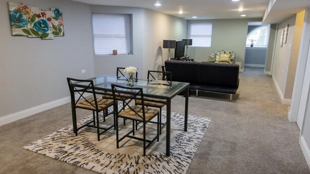 Un comedor con una mesa de vidrio y sillas, un sofá y un tapete decorativo.