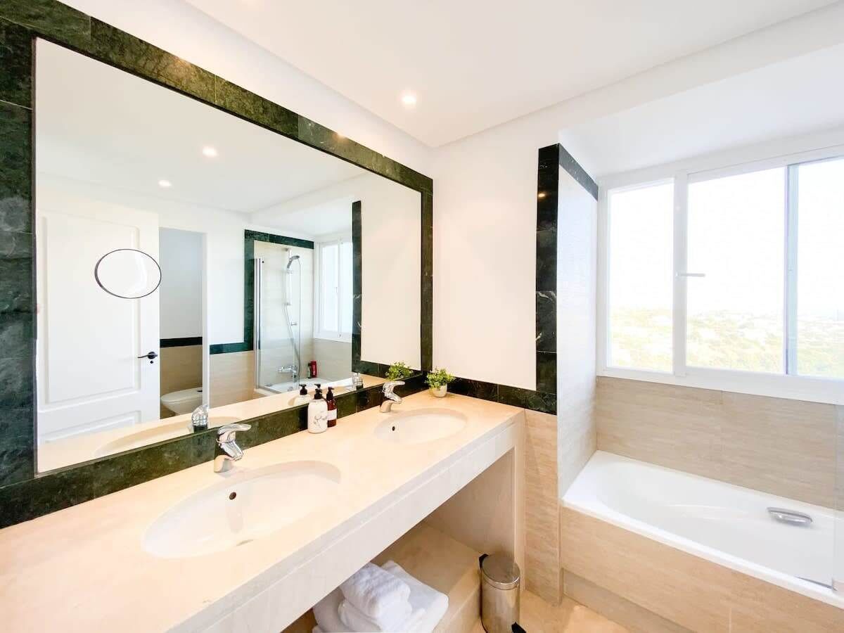 Un baño moderno con dos lavamanos, un espejo grande y una bañera.
