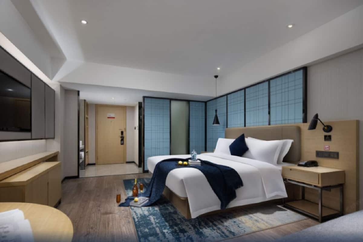 Una habitación de hotel moderna con una cama grande, mesitas de noche, un escritorio y un televisor.